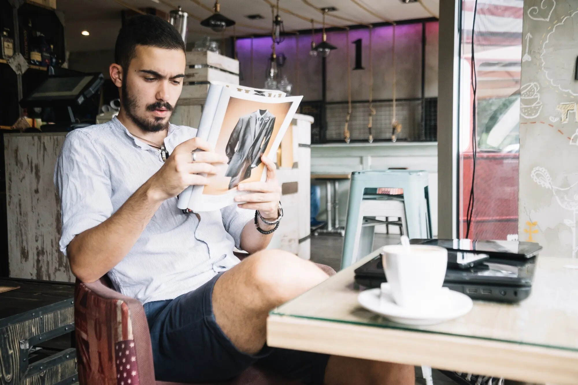 Gutaussehender Mann, der im Café mit einer Zeitschrift entspannt.